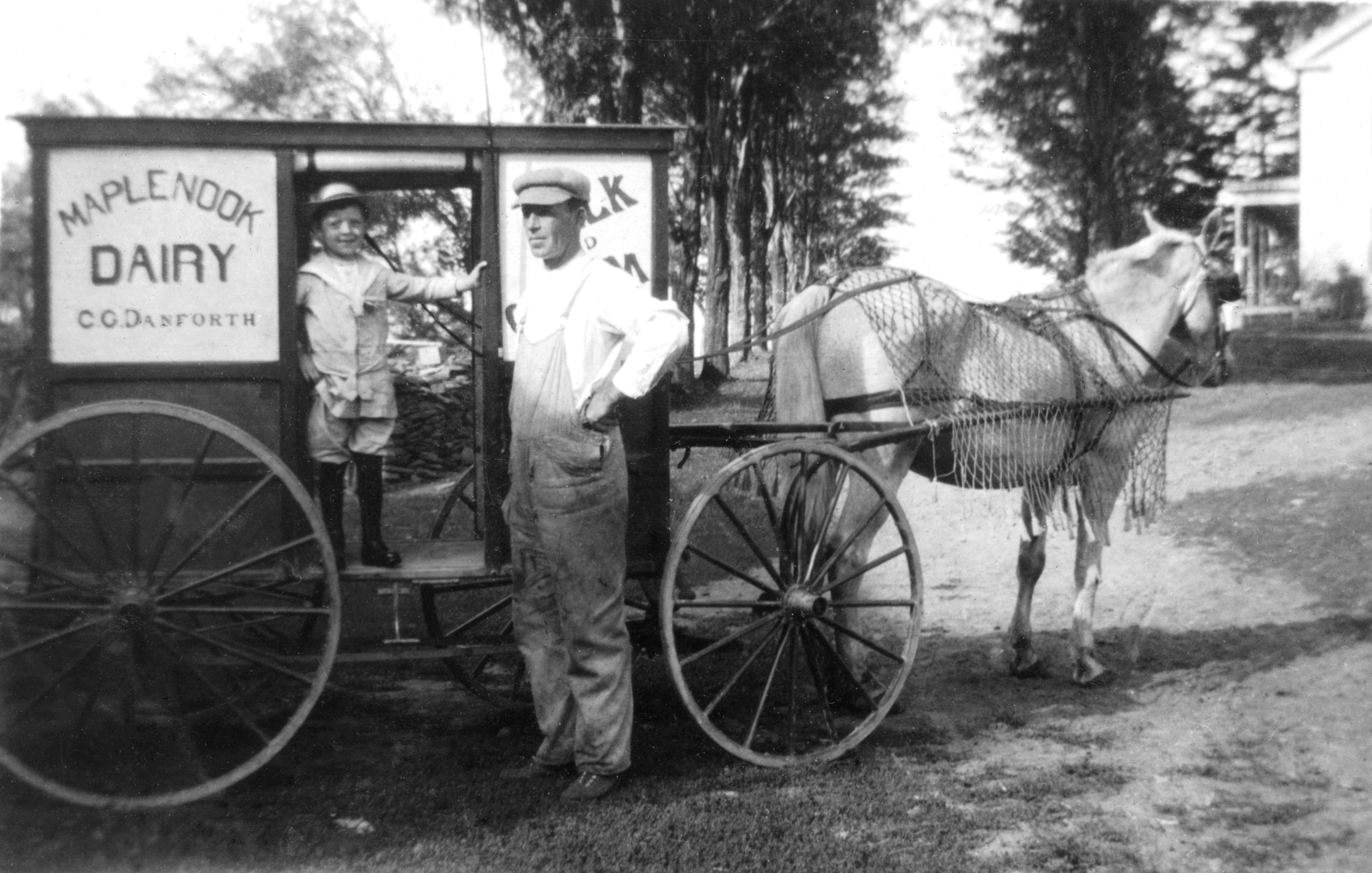Man and child next to horse drawn milk carriege
